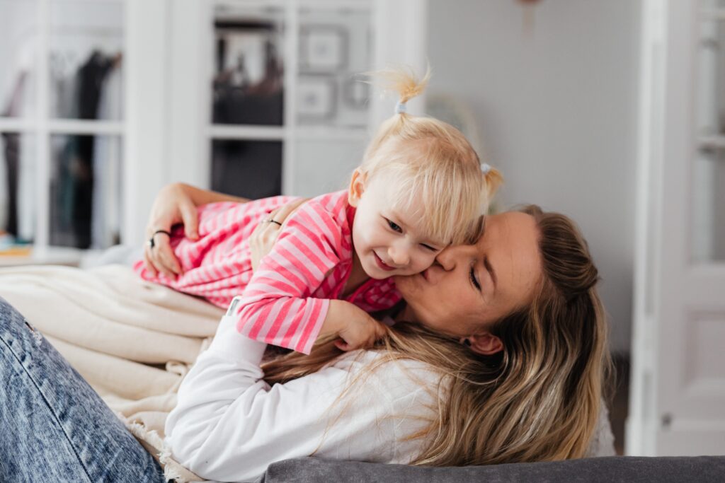 Woman and young child playing together on a bed at home.